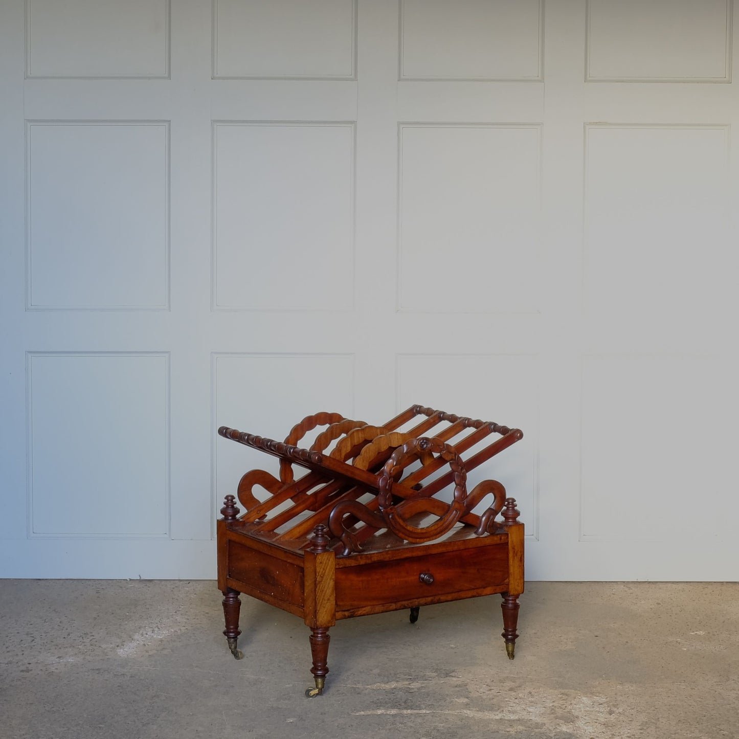 A beautiful mahogany canterbury, circa 1820, with five cross framed dividers incorporating a laurel wreath motif. With a single drawer below and raised on turned legs with original castors. In very good condition.