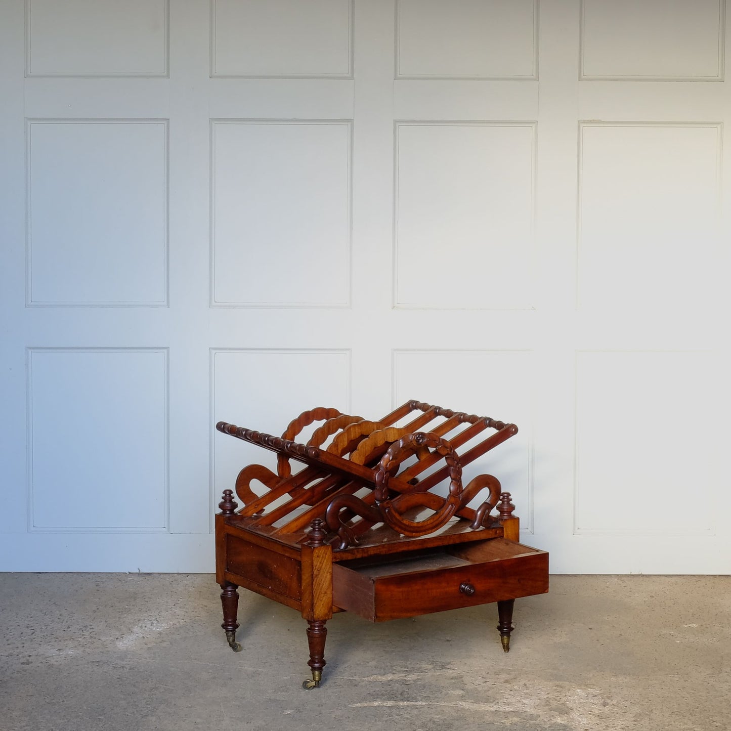 A beautiful mahogany canterbury, circa 1820, with five cross framed dividers incorporating a laurel wreath motif. With a single drawer below and raised on turned legs with original castors. In very good condition.
