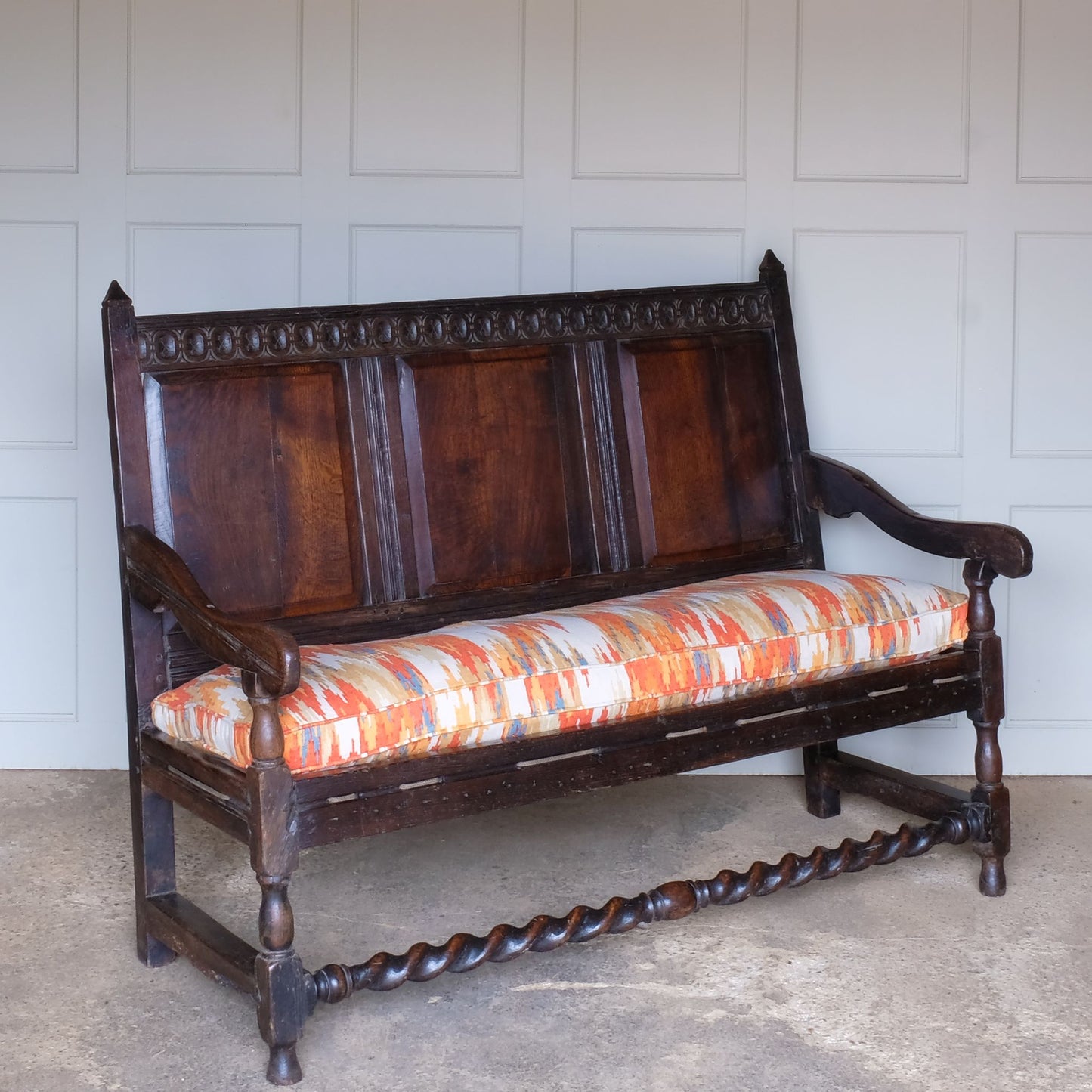 A side angle view of Vintage 18th Century Oak Settle with Upholstered Cushion - Summerfield & Scott