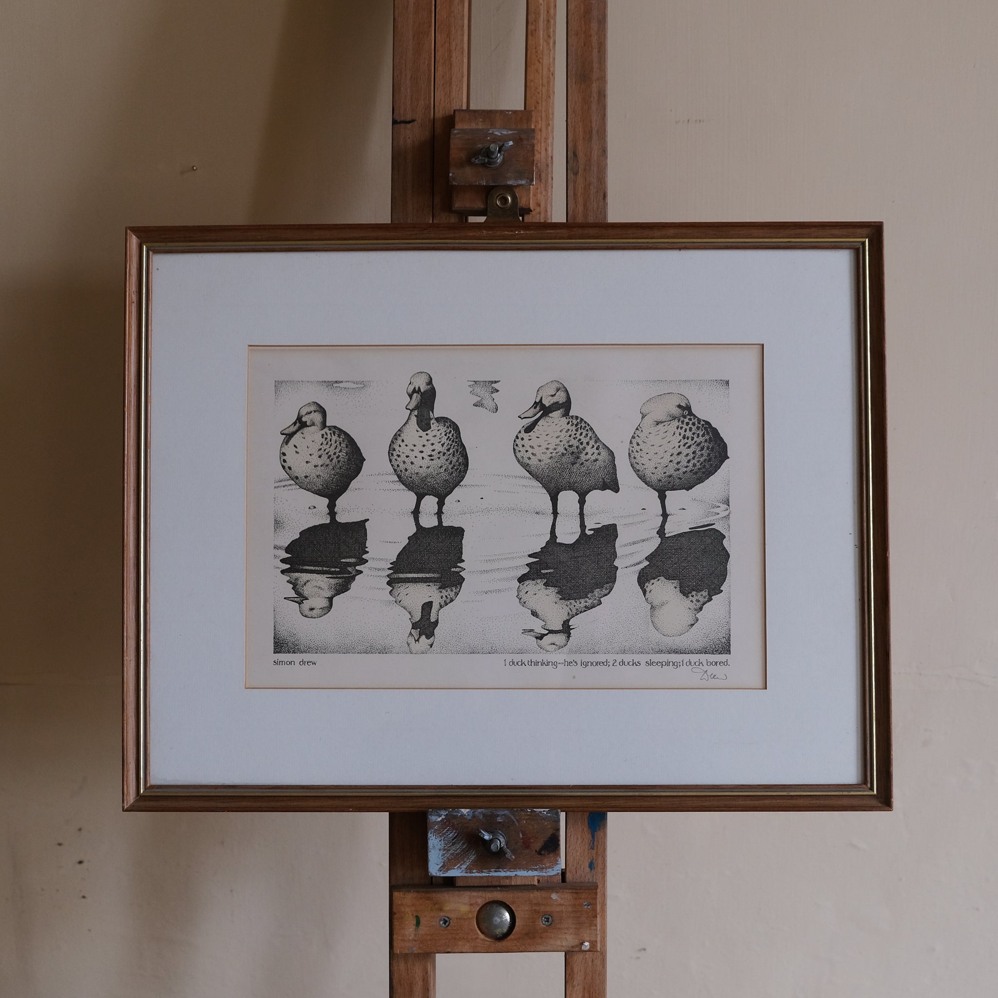 Framed artwork of ducks on a reflective surface on an easel.