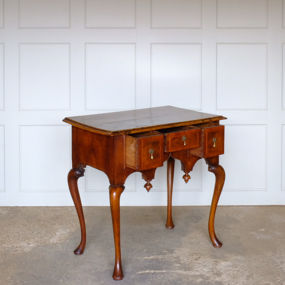 A George I walnut and feather banded side table, c. 1720. Inlaid detail to the top and a shaped apron with finials, likely added later. A delightful patina commensurate with age throughout.