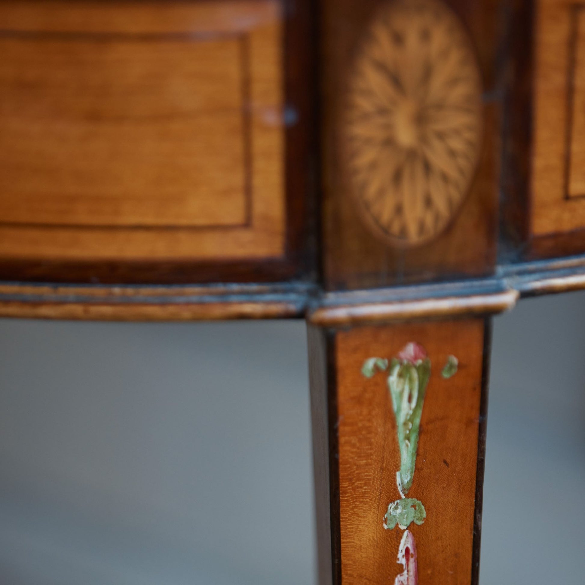 A George III satinwood and marquetry demilune folding card table, with a fold over top fitted with green baize. The top features a beautiful fan inlay and crossbanding around the outside, with the frieze incorporating purple heart crossbanding, over four elegantly tapering legs with floral painted decoration. The rear legs are hinged to swing out and support the folding top. In very good, sturdy overall condition. Would work well as a side console table, or a centre hall table.