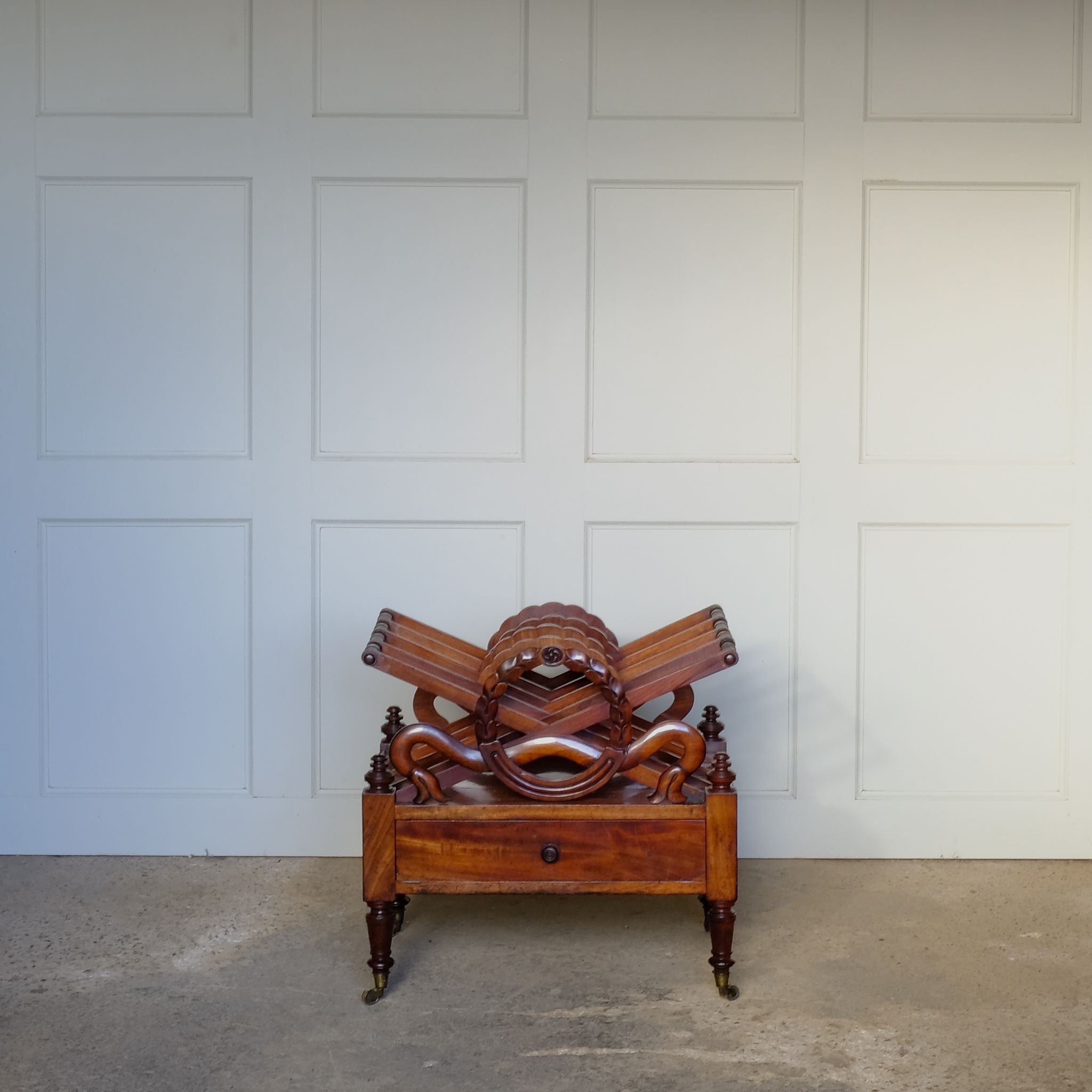 A beautiful mahogany canterbury, circa 1820, with five cross framed dividers incorporating a laurel wreath motif. With a single drawer below and raised on turned legs with original castors. In very good condition.