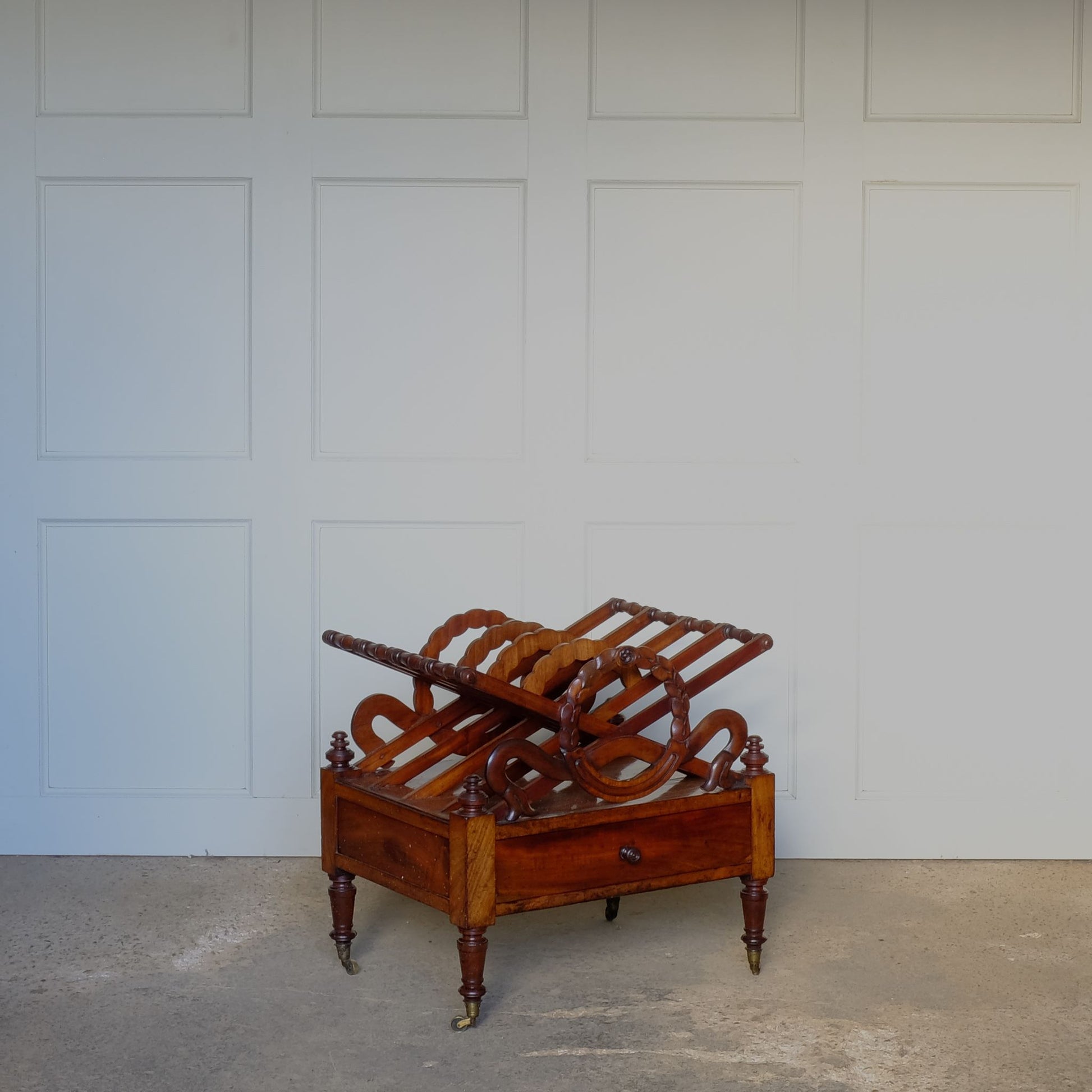 A beautiful mahogany canterbury, circa 1820, with five cross framed dividers incorporating a laurel wreath motif. With a single drawer below and raised on turned legs with original castors. In very good condition.