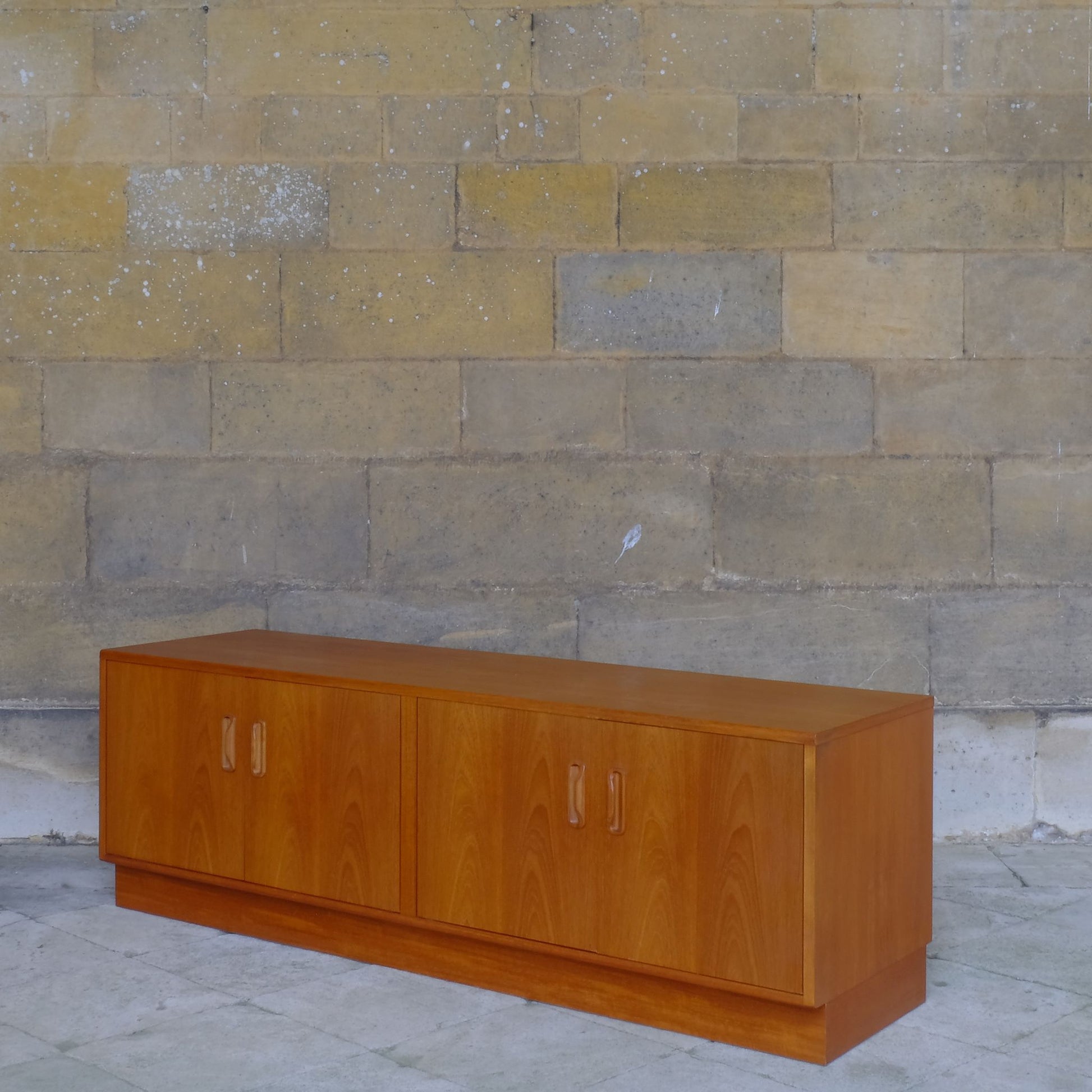 A low teak mid century sideboard by G Plan. Two spacious cabinets, each with a pair of doors and single internal shelf. The maker's mark is present inside one of the doors. In lovely condition, with some very light marks to the top, commensurate with the item's age.