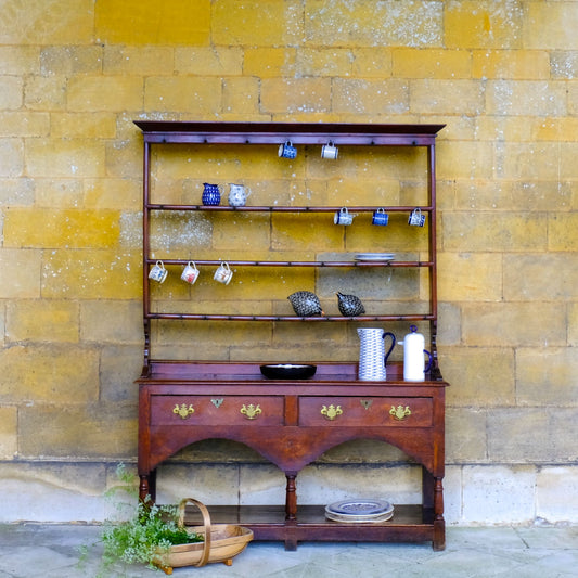 An 18th century dresser in a beautiful rich oak, with open plate shelves over a two drawer base with a twin arched apron on turned legs with a boarded lower shelf. Various hooks along the three shelves and top. Comes in two pieces for easy transport and maneuver. A delightful patina commensurate with age throughout, with some faint signs of an old green tint to the top of the shelves. In very good solid structural condition.