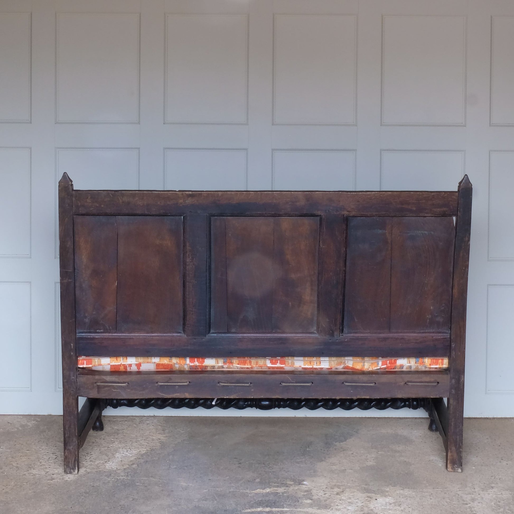 An exquisite 18th century oak settle with a carved back panel on turned legs with a barley twist front stretcher. In good, sturdy condition with a really beautiful, rich patina. The seat has been re-corded, and a new feather cushion made for it, upholstered in "Thika" by Jim Thompson, sourced from Haines Collection. Below this cushion sits a slim pad which has been made to protect the upholstery from wear from the cording.