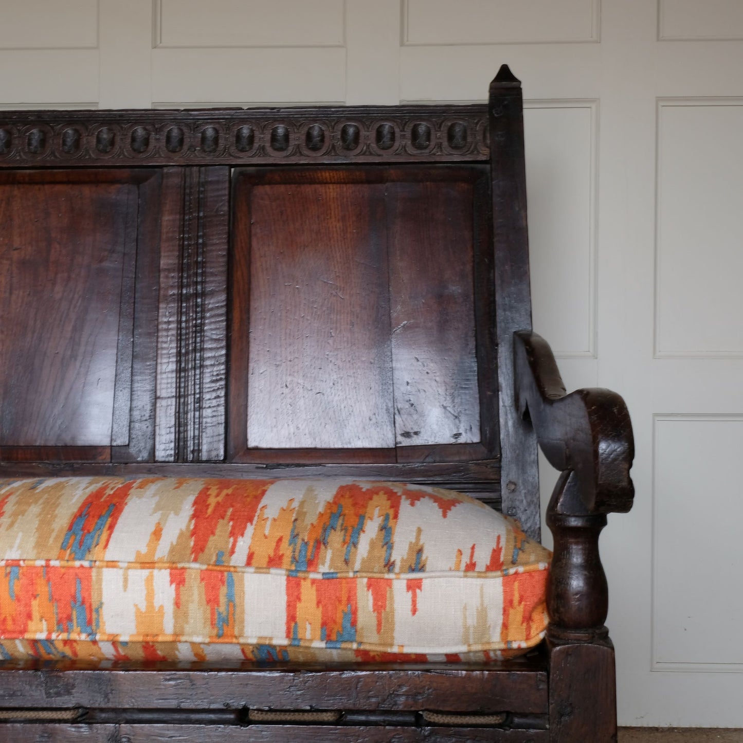 An exquisite 18th century oak settle with a carved back panel on turned legs with a barley twist front stretcher. In good, sturdy condition with a really beautiful, rich patina. The seat has been re-corded, and a new feather cushion made for it, upholstered in "Thika" by Jim Thompson, sourced from Haines Collection. Below this cushion sits a slim pad which has been made to protect the upholstery from wear from the cording.