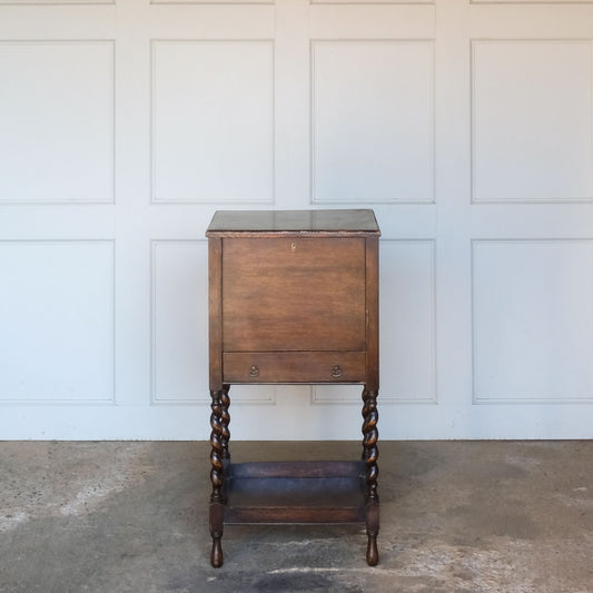 A late 19th / early 20th century oak sewing table, with a hinged top and single drawer below, on elegant barley twist supports over a single shelf and turned feet, the interior of the upper cabinet and drawer lined with burnt orange silk padding, with some age related patina, in very good condition. It would make a lovely bedside table.