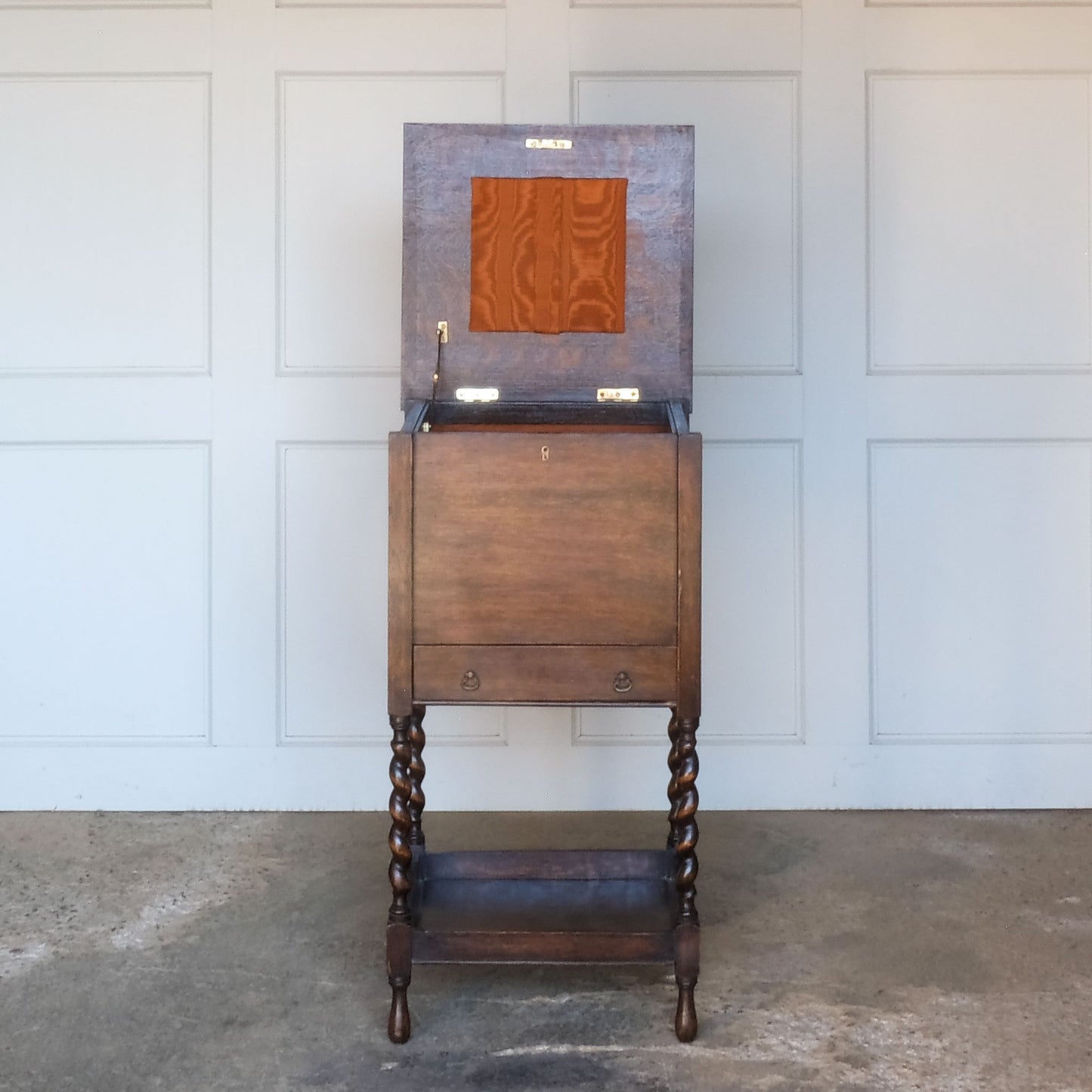 A late 19th / early 20th century oak sewing table, with a hinged top and single drawer below, on elegant barley twist supports over a single shelf and turned feet, the interior of the upper cabinet and drawer lined with burnt orange silk padding, with some age related patina, in very good condition. It would make a lovely bedside table.