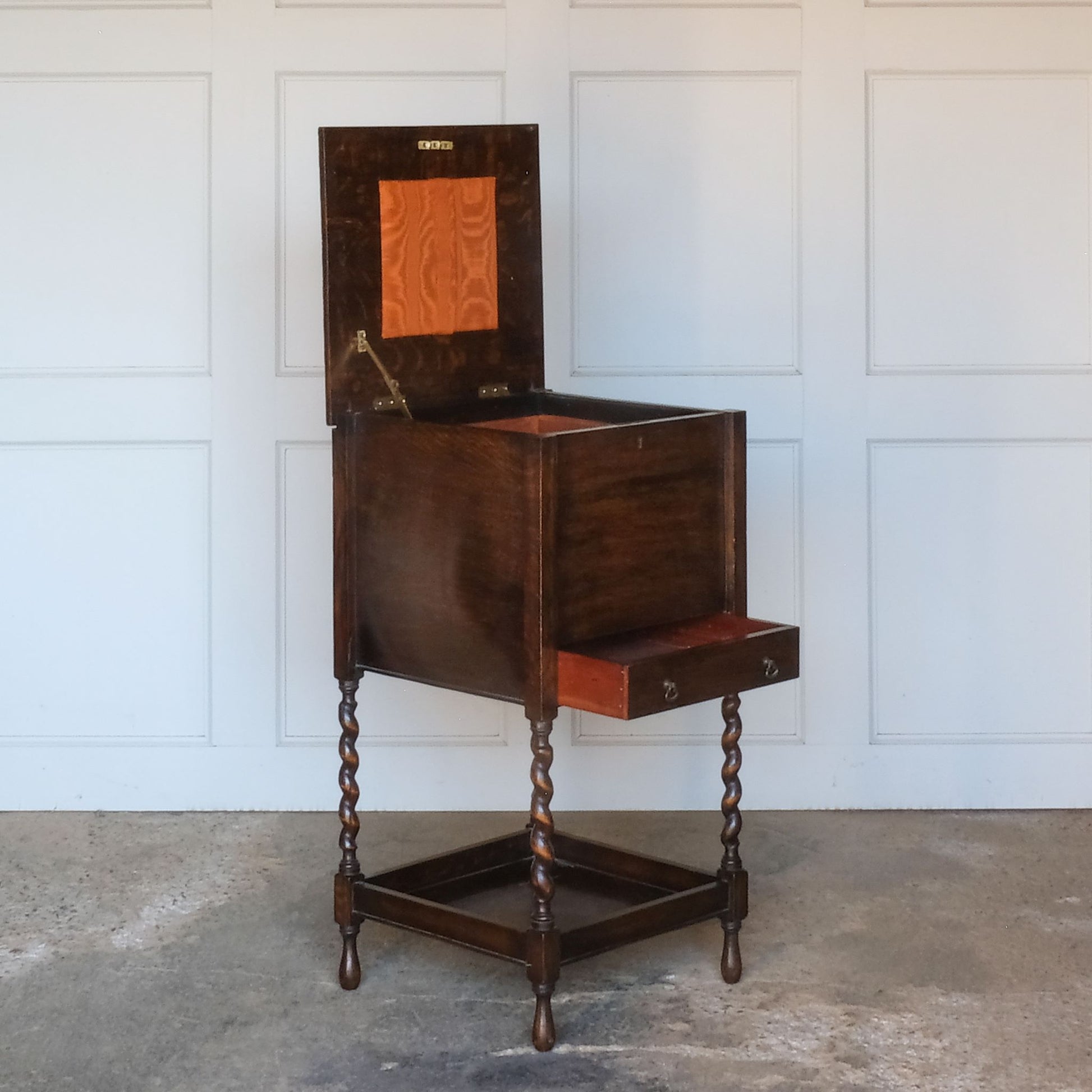 A late 19th / early 20th century oak sewing table, with a hinged top and single drawer below, on elegant barley twist supports over a single shelf and turned feet, the interior of the upper cabinet and drawer lined with burnt orange silk padding, with some age related patina, in very good condition. It would make a lovely bedside table.