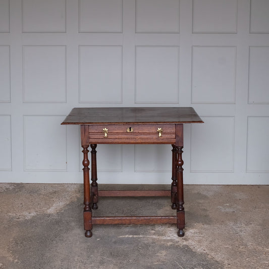 A fine 17th century English oak side table with a lovely well-patinated two plank moulded top with with flying overhangs above a single drawer over tapered and ring-turned legs joined by box stretchers. A very useful size for use in either a living room, small hallway or as an elegant bedside table.