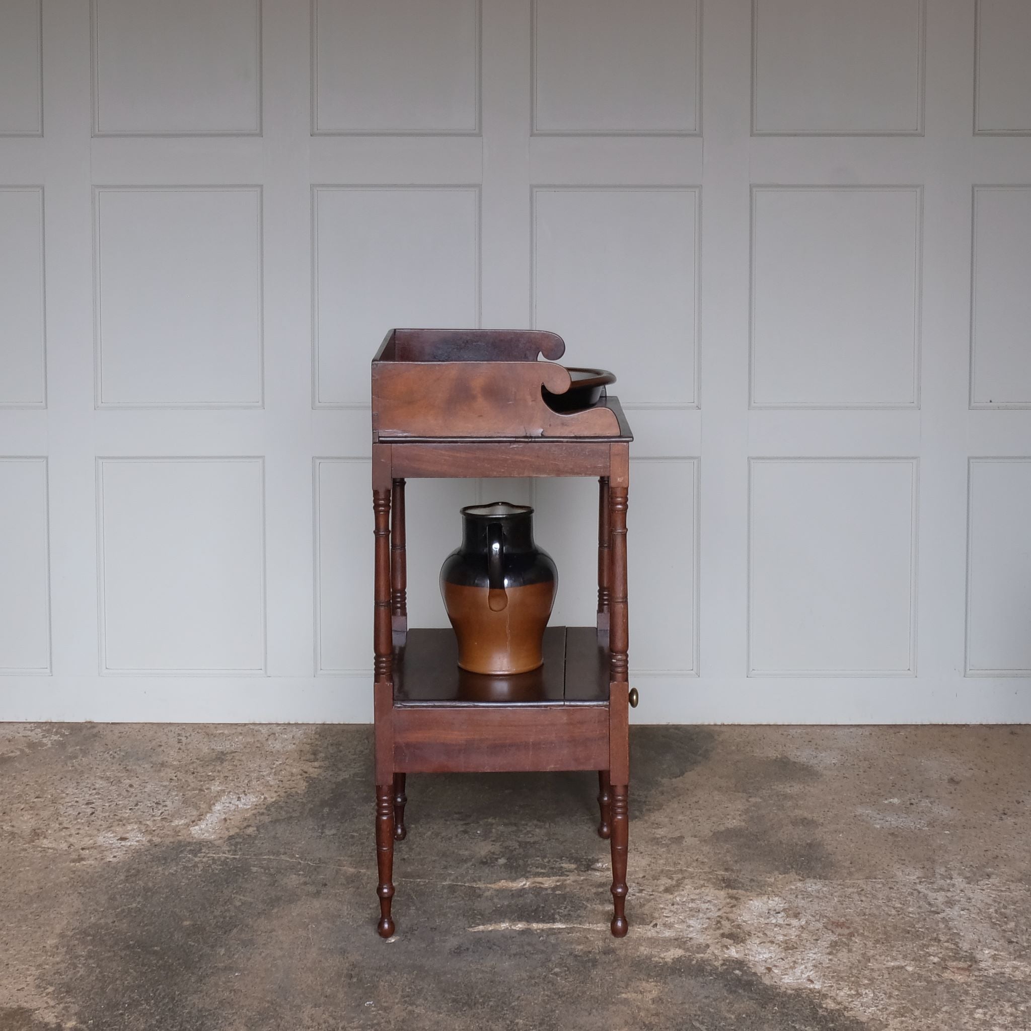 A charming early Victorian mahogany washstand, the three quarter gallery with a basin recess on turned and ringed uprights, over a single shelf with drawer over turned and ringed legs, also comprising a later stoneware basin and jug, with a gentle patina and wear commensurate with age and use, otherwise in good condition.