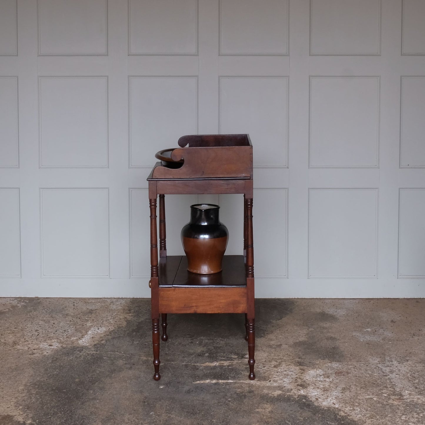 A charming early Victorian mahogany washstand, the three quarter gallery with a basin recess on turned and ringed uprights, over a single shelf with drawer over turned and ringed legs, also comprising a later stoneware basin and jug, with a gentle patina and wear commensurate with age and use, otherwise in good condition.
