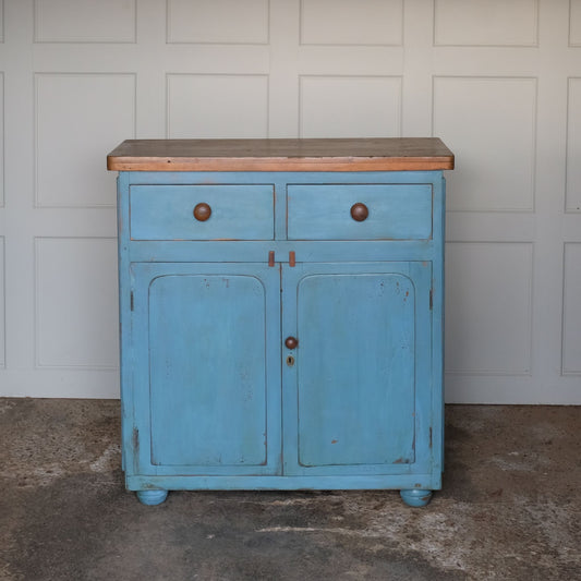A beautiful powder blue painted cupboard, with an unpainted oak top over two drawers, above cupboard doors revealing a single shelf interior finished in a lightly contrasting yellow, on four bun feet. A lovely patina commensurate with age and use, in very good condition throughout.