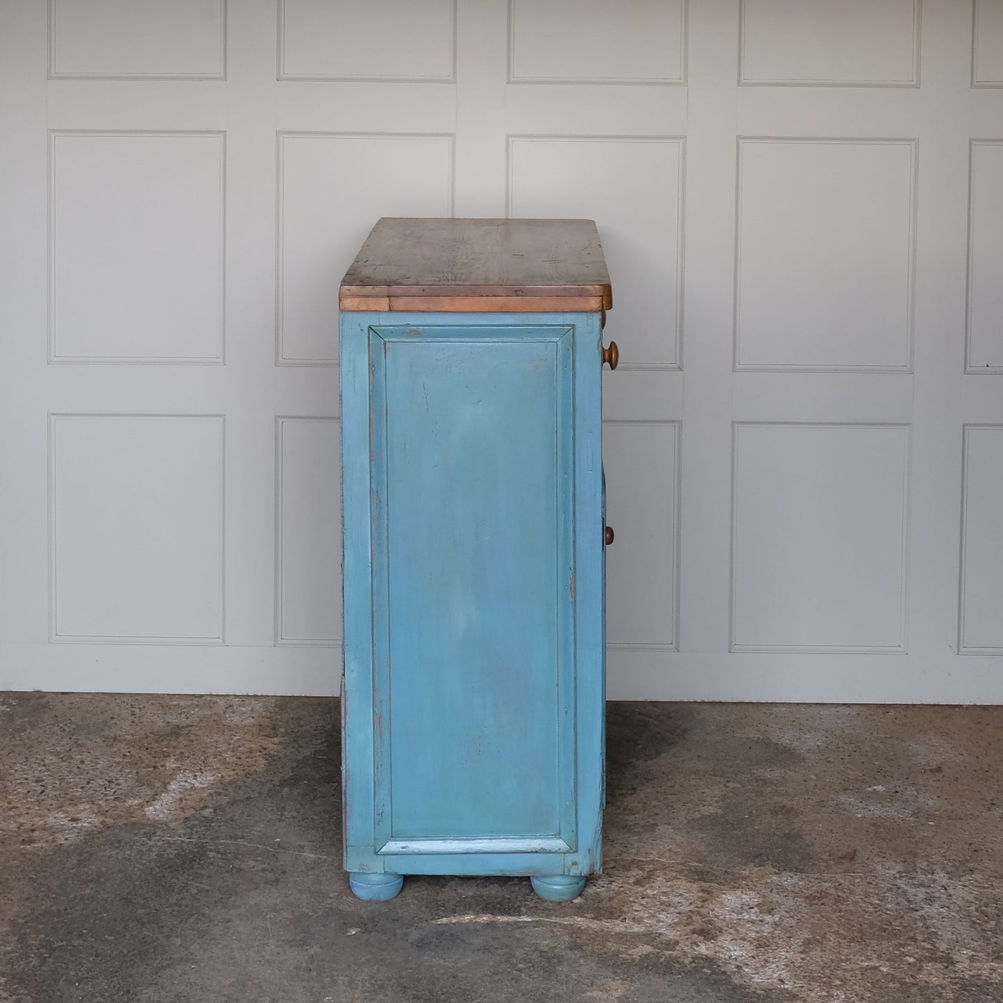 A beautiful powder blue painted cupboard, with an unpainted oak top over two drawers, above cupboard doors revealing a single shelf interior finished in a lightly contrasting yellow, on four bun feet. A lovely patina commensurate with age and use, in very good condition throughout.