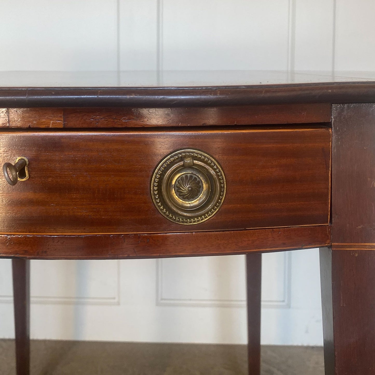 A charming George III mahogany Pembroke table, an oval top with delicate boxwood stringing at the edges over a single drawer, with working key, a dummy drawer matching on the other side, over square tapering legs on brass casters, some minor scuffing to the top and legs commensurate with age, otherwise in very good condition.