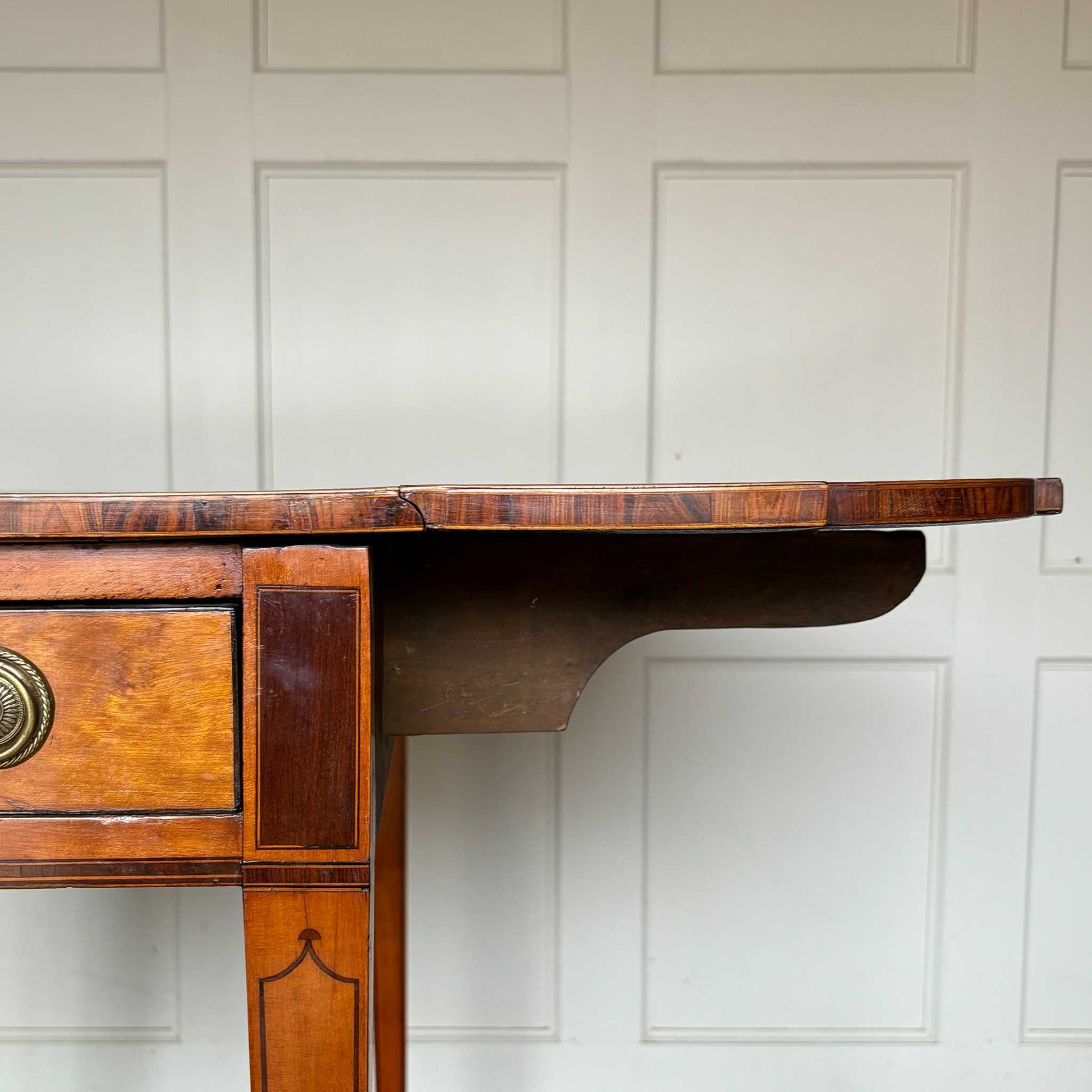 A lovely George III satinwood Pembroke table, the shaped drop leaf top with elegant crossbanding above a single end drawer with a dummy drawer on the opposing side, raised on gently tapering square legs with delicate inlay detailing over brass castors, with some gentle surface patina to the top as is commensurate with age and use, in very good condition