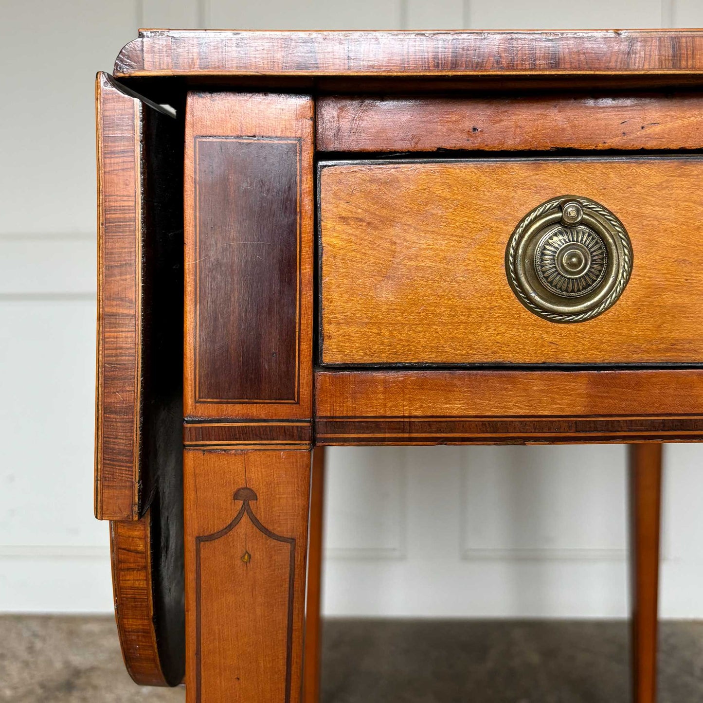 A lovely George III satinwood Pembroke table, the shaped drop leaf top with elegant crossbanding above a single end drawer with a dummy drawer on the opposing side, raised on gently tapering square legs with delicate inlay detailing over brass castors, with some gentle surface patina to the top as is commensurate with age and use, in very good condition
