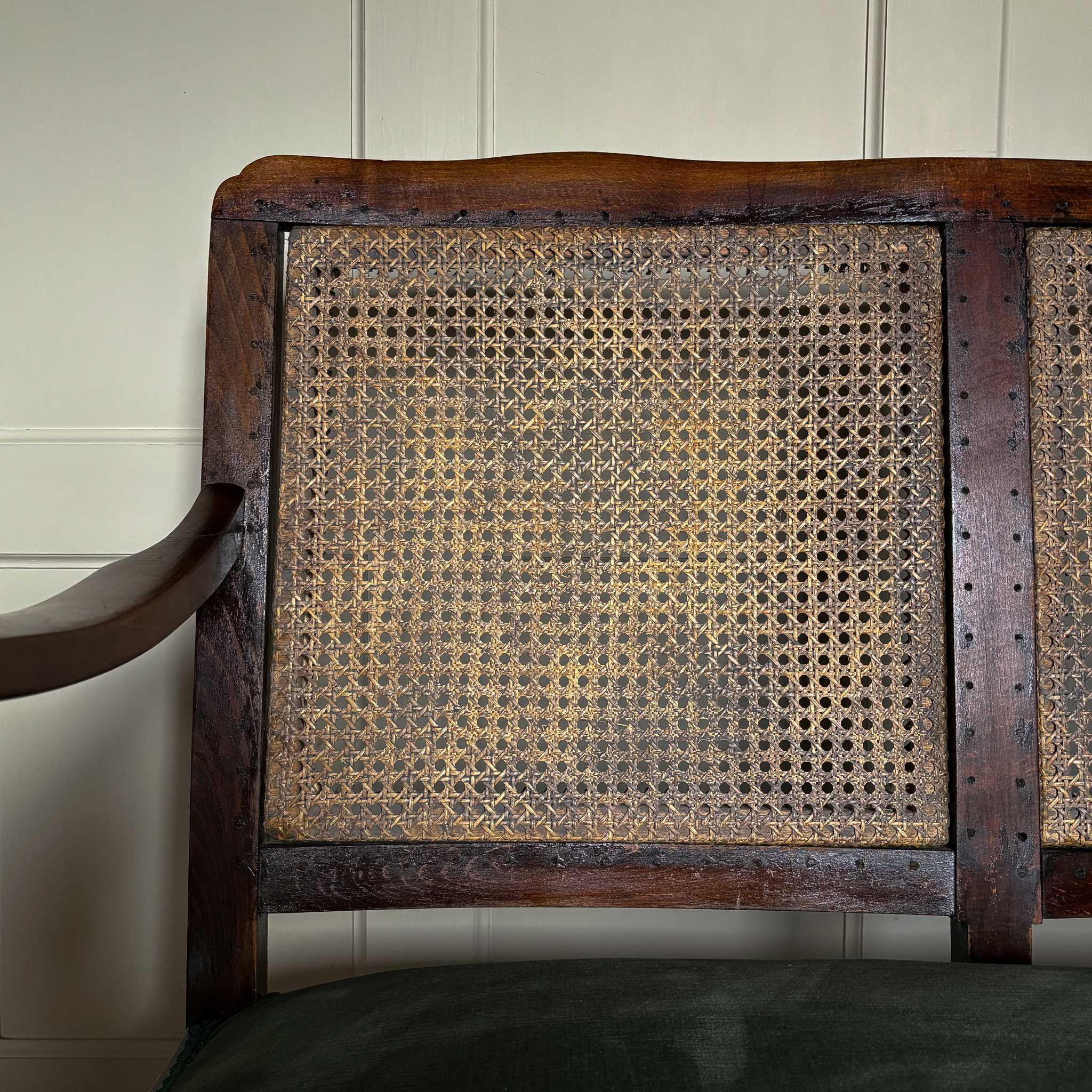 Close up detail of left side of cane backed vintage settee by Summerfield & Scott