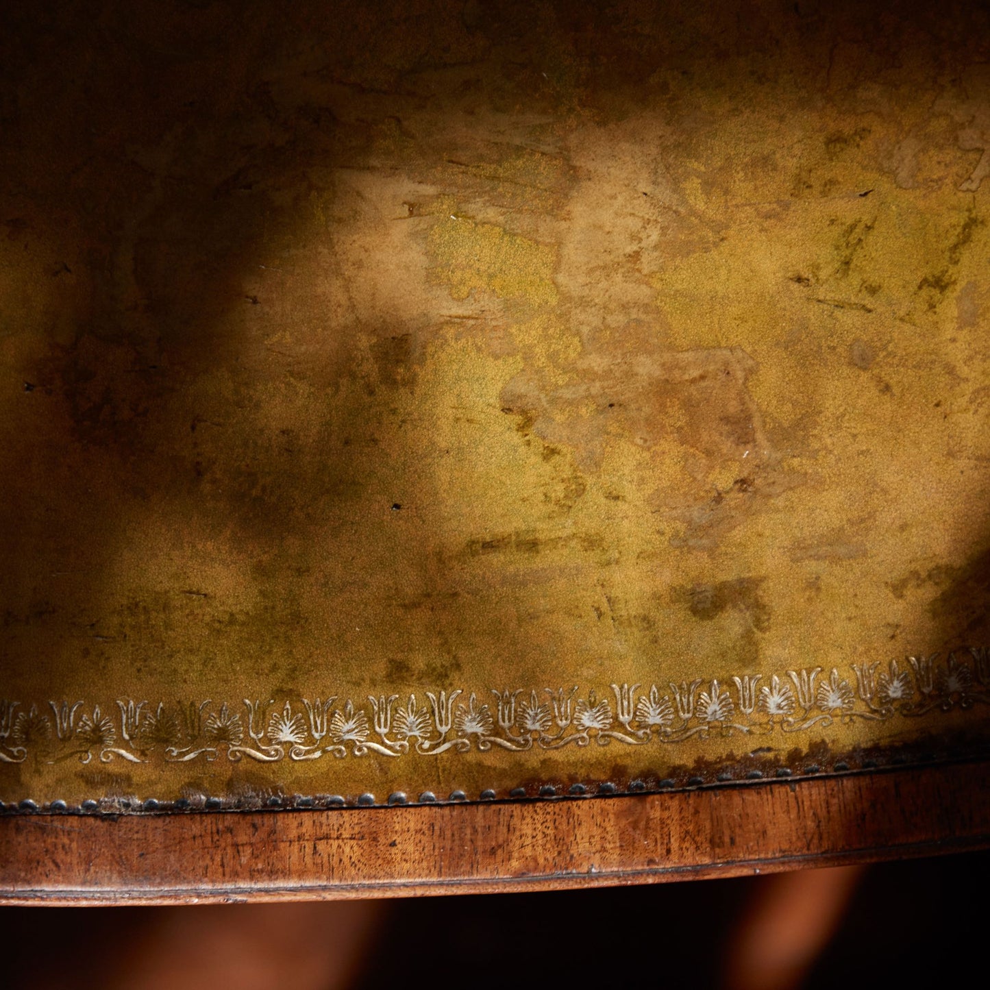 A stunning and rare George III library table, circa 1810, with original leather top with a magnificent, verdigris-like patina. A pair of frieze drawers to the front with false drawers on the reverse, over a beautifully arched crossband down to divided legs, each with a decorative scroll detailing, on period casters. The drawers can be locked with a single key. With a gentle patina commensurate with age and use, in very good condition.