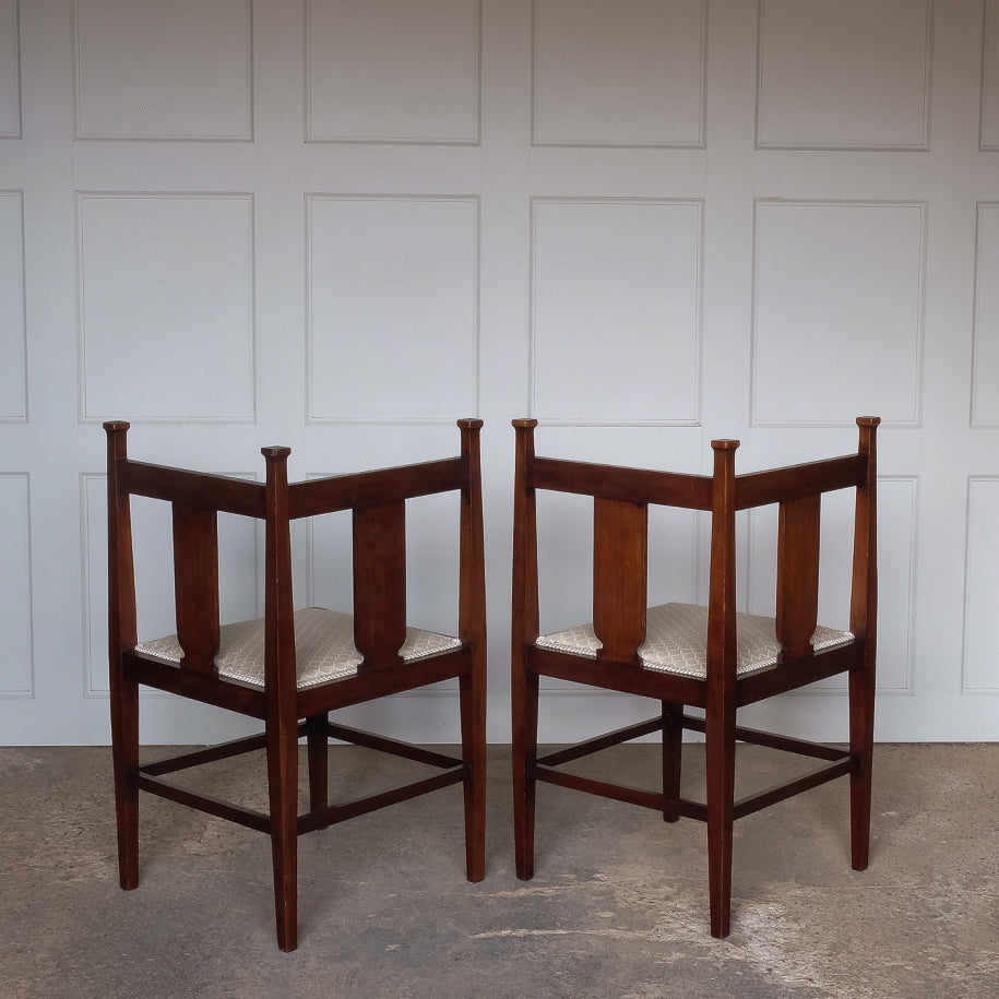 A pair of Arts and Crafts inlaid mahogany corner chairs, with floral design inlay to the backs and recently upholstered seat bases, in very good condition.