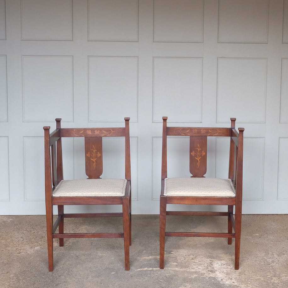 A pair of Arts and Crafts inlaid mahogany corner chairs, with floral design inlay to the backs and recently upholstered seat bases, in very good condition.