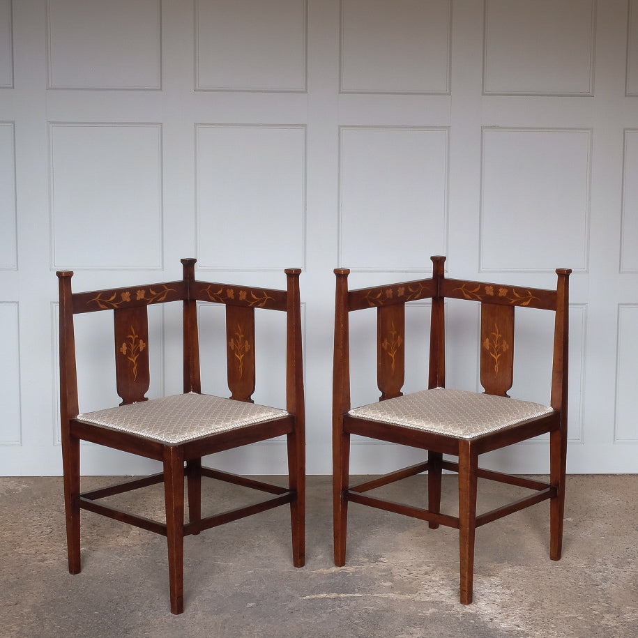 A pair of Arts and Crafts inlaid mahogany corner chairs, with floral design inlay to the backs and recently upholstered seat bases, in very good condition.