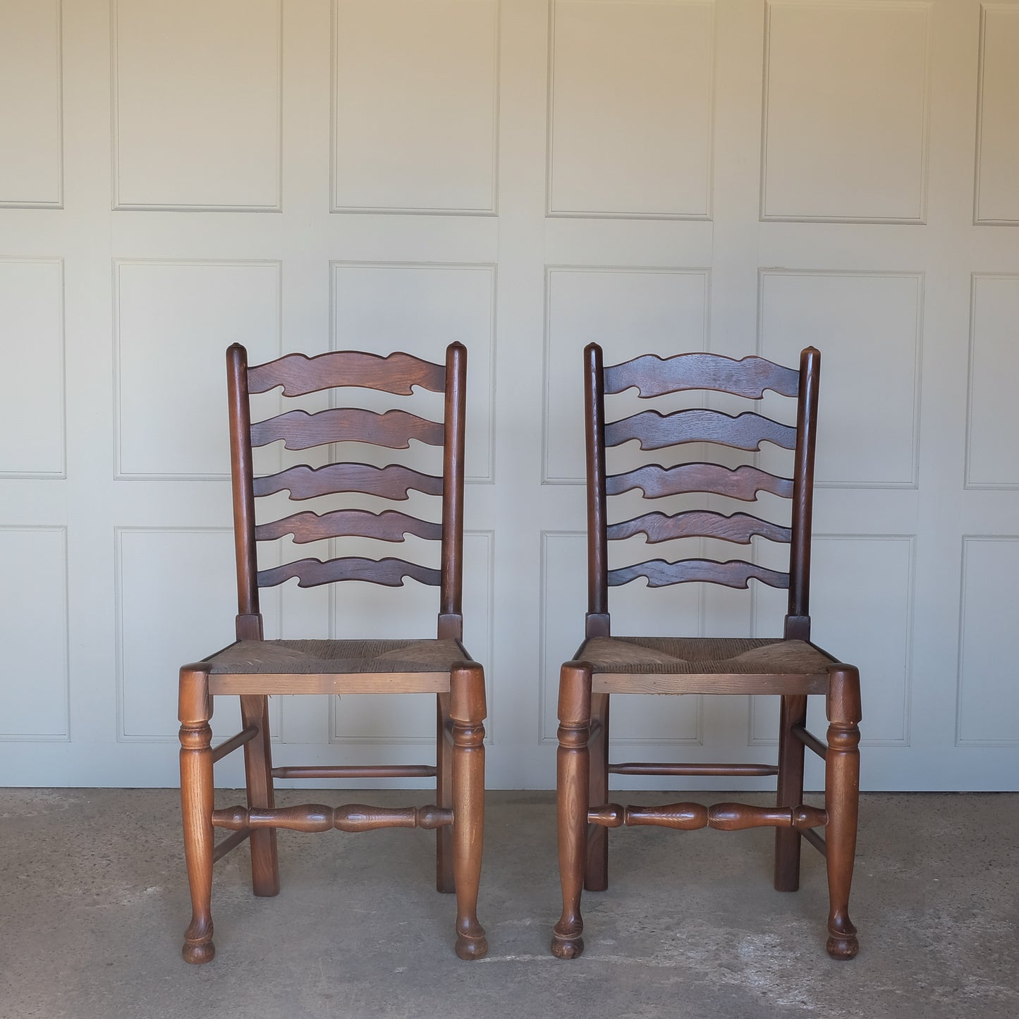 A PAIR OF OAK LADDER BACK CHAIRS