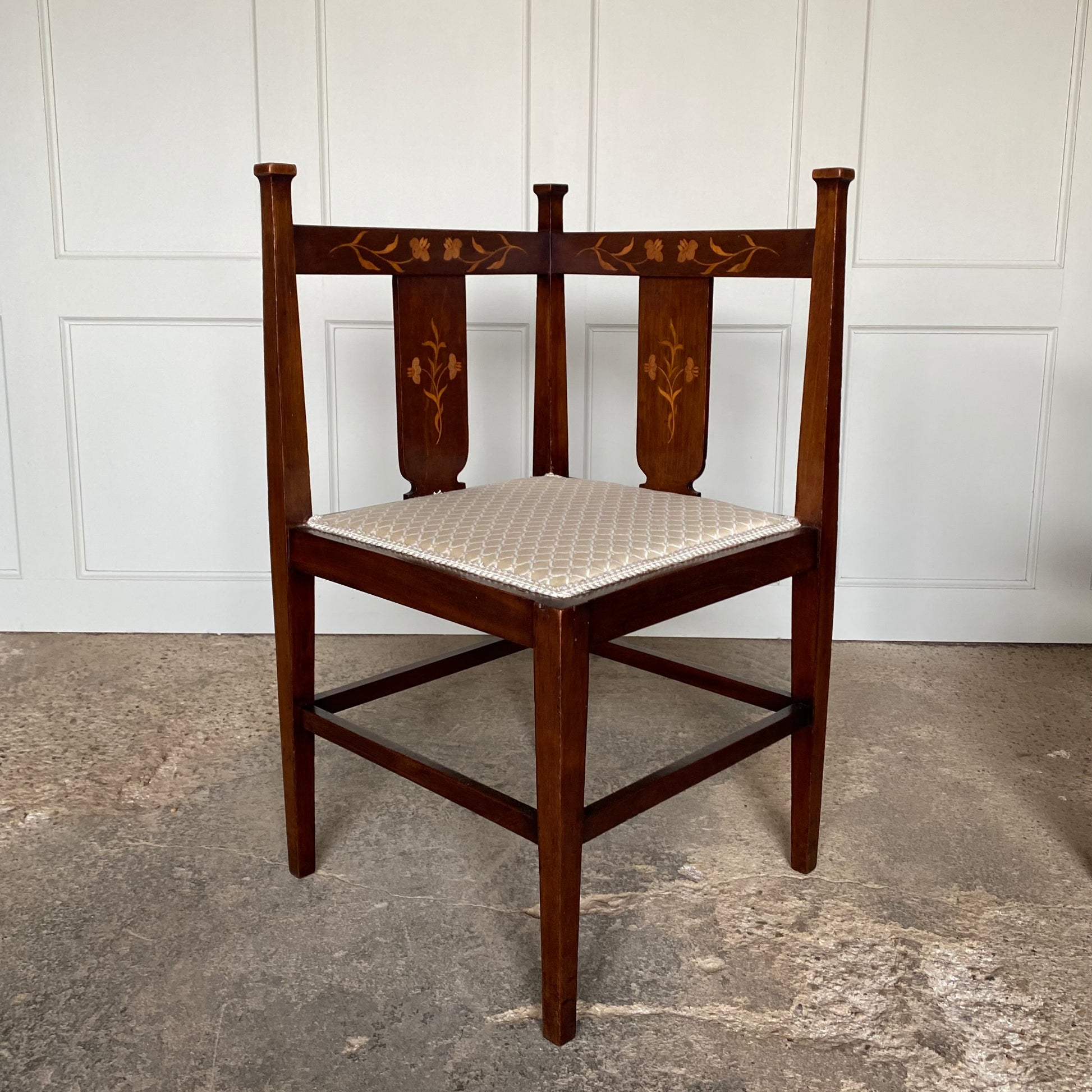 A pair of Arts and Crafts inlaid mahogany corner chairs, with floral design inlay to the backs and recently upholstered seat bases, in very good condition.